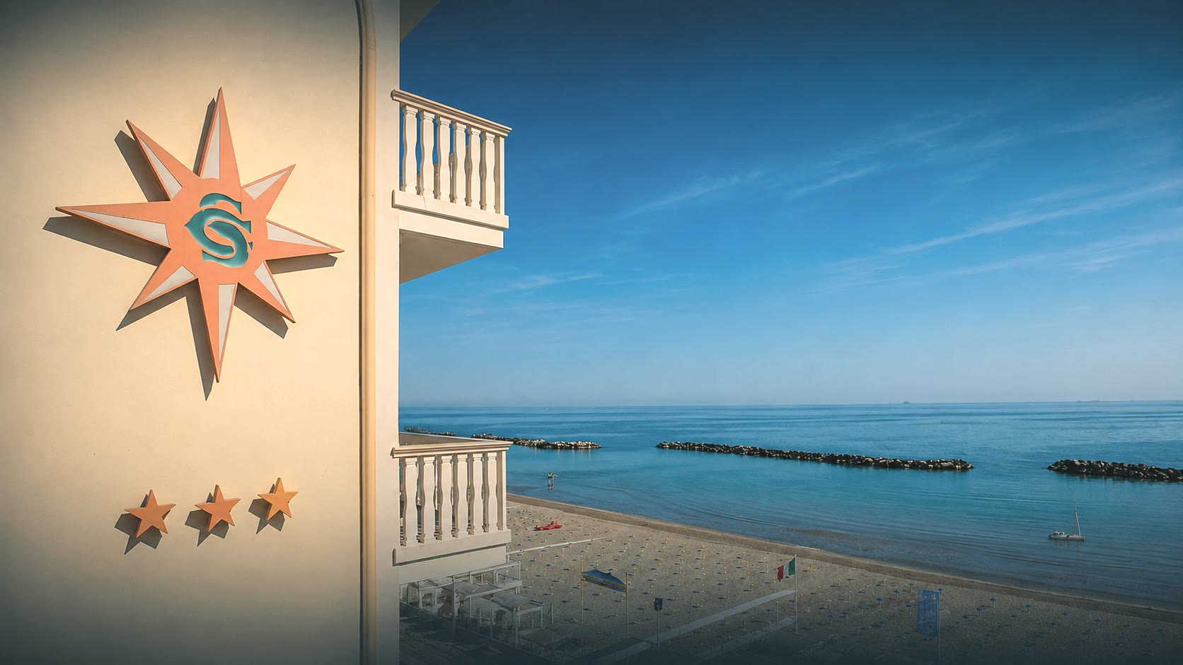 La facciata dell'Hotel Croce del Sud con la rosa dei venti, il balcone e il mare di Bellaria